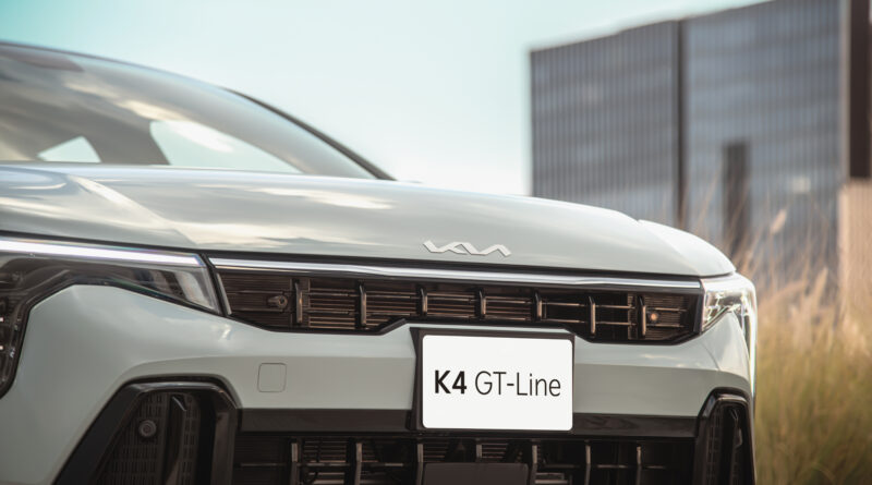 Sedán compacto Kia K4 color gris con diseño fastback circulando en ciudad, ganador del premio MotorWeek 2026.